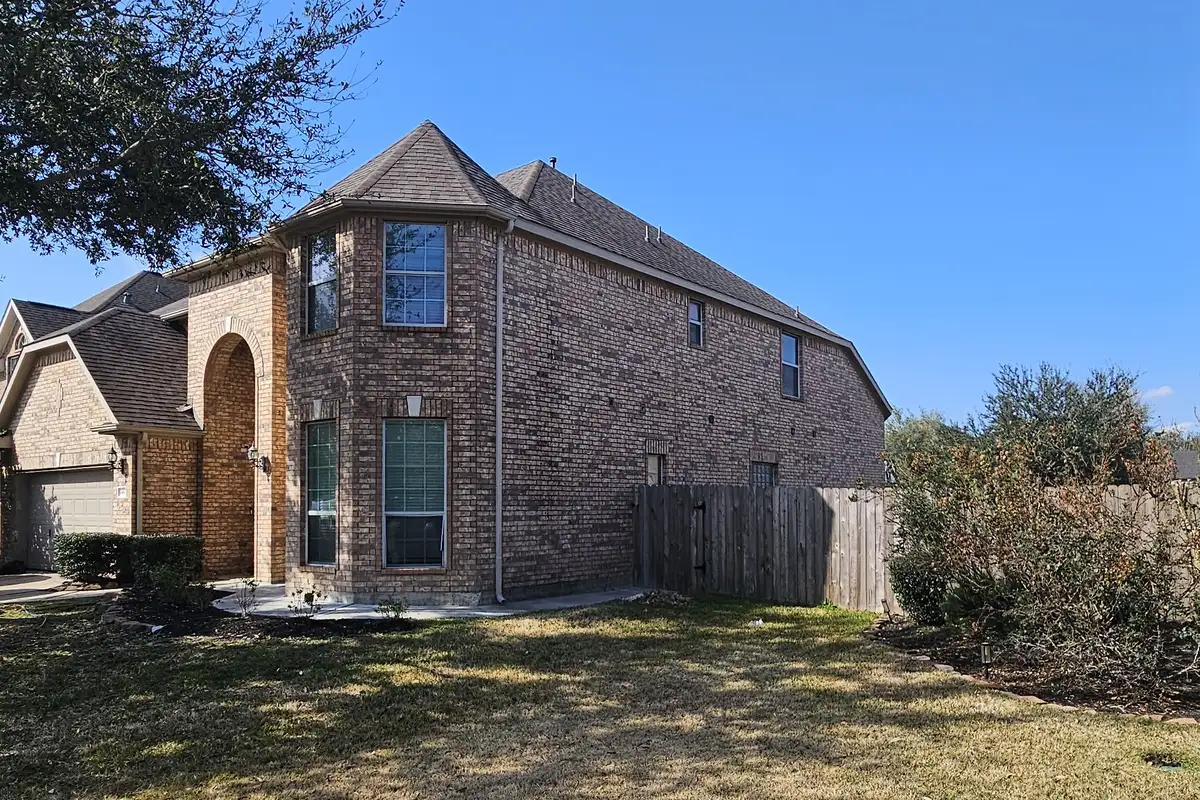 Asphalt shingle roof above a two-story brick home.